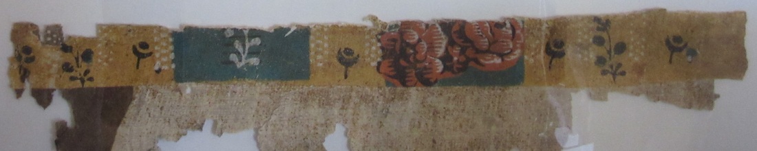 Fragment of wallpaper from a bedroom at the Morris-Jumel Mansion. Pattern of sprigs and flowers  on a ground of mustard yellow and slate blue stripe.